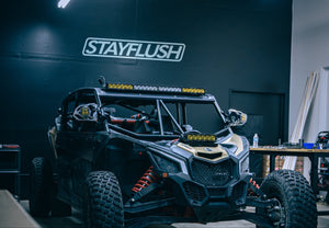 Off-road vehicle in a workshop with 'STAYFLUSH' branding on the wall.