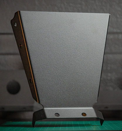 The StayFlush Clean Slate Console – Universal Blank Build Platform by StayFlush Motorsports stands upright on a green cutting mat, showing its textured metal surface, angled edges, and two holes against a blurred gray background.