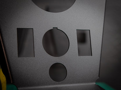 A close-up of the StayFlush Cyclops Console + 2-Switch by StayFlush Motorsports: dark gray, textured matte metal panel with five cut-outs—a large circle, small circle, two rectangles, and a small semicircle.